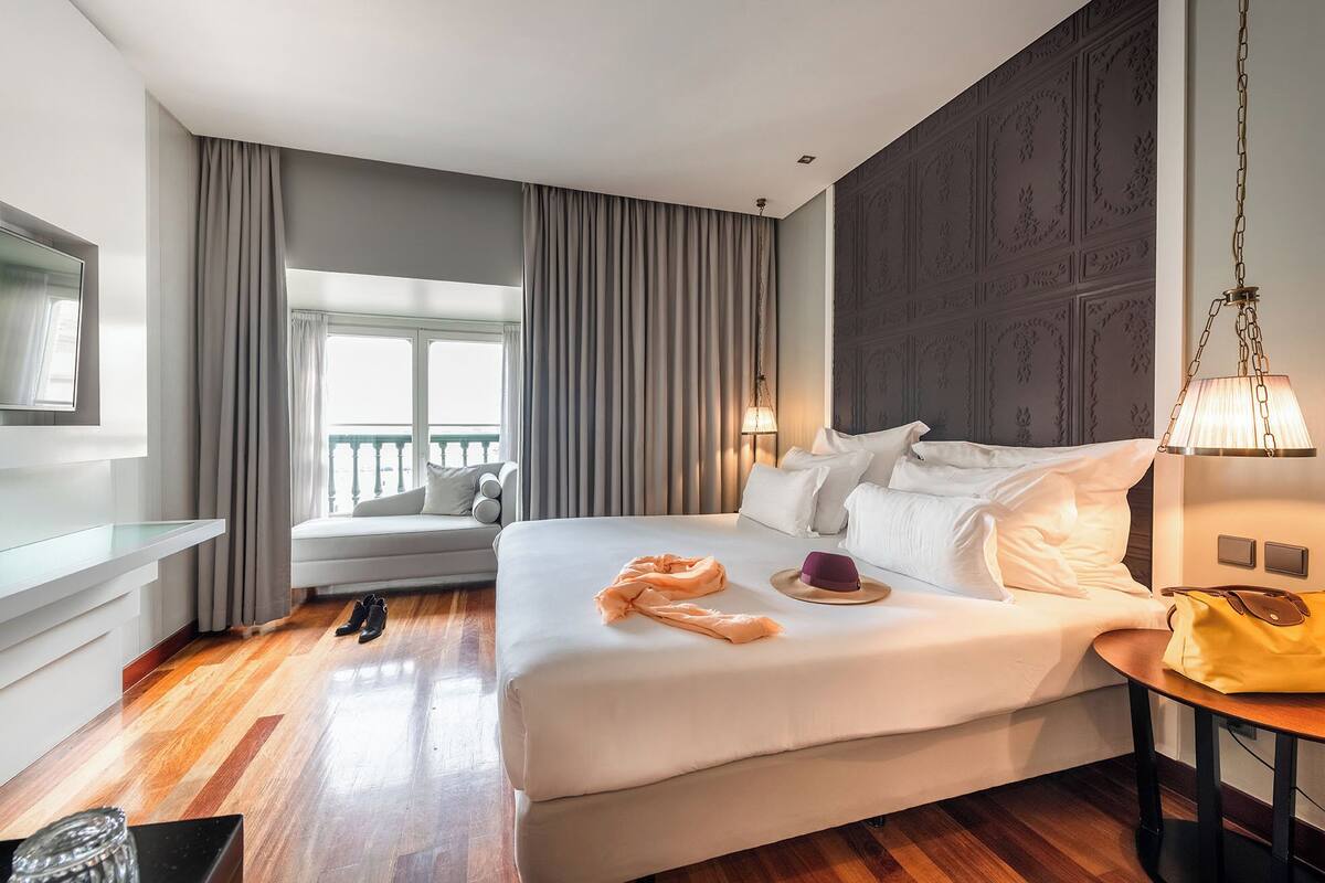 Habitación de hotel con una cama grande, zona de estar con vistas, televisor y lámpara.
