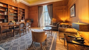 A spacious living room with a wooden bookshelf, a dining area with chairs, a sofa, a coffee table, and a chandelier. - Pousada de Lisboa - Small Luxury Hotels Of The World (Lisbon)