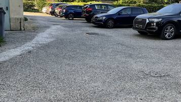 Un estacionamiento con varios coches, incluyendo un Audi SUV, y un edificio de fachada de hormigón.