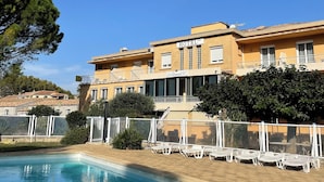 A hotel with a swimming pool, outdoor seating, and a clear blue sky. - Hotel Le Clément V (Roquemaure)