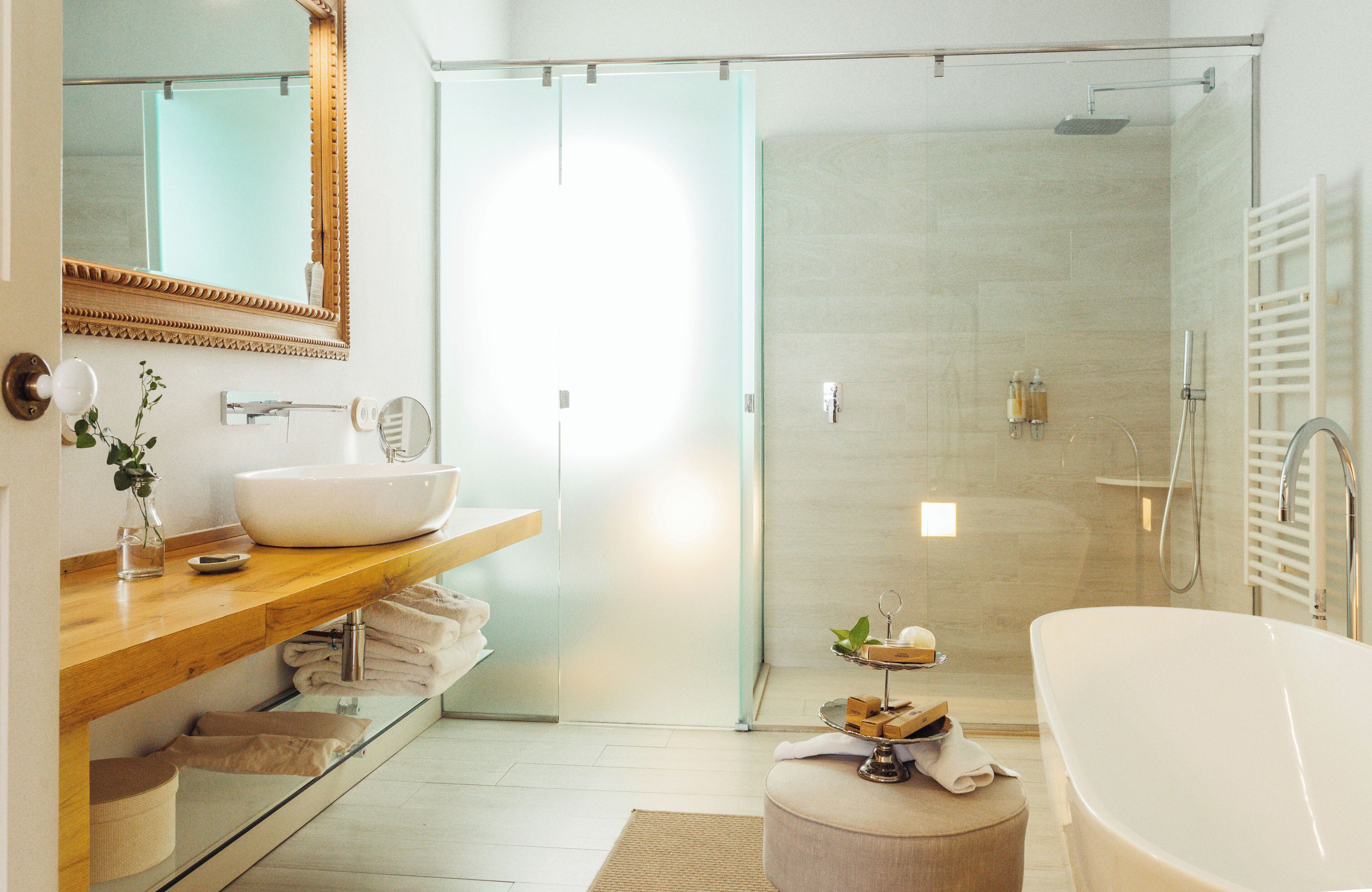 Une salle de bain moderne avec une baignoire sur pieds, une douche à parois de verre et un meuble-lavabo en bois doté d’un grand miroir.