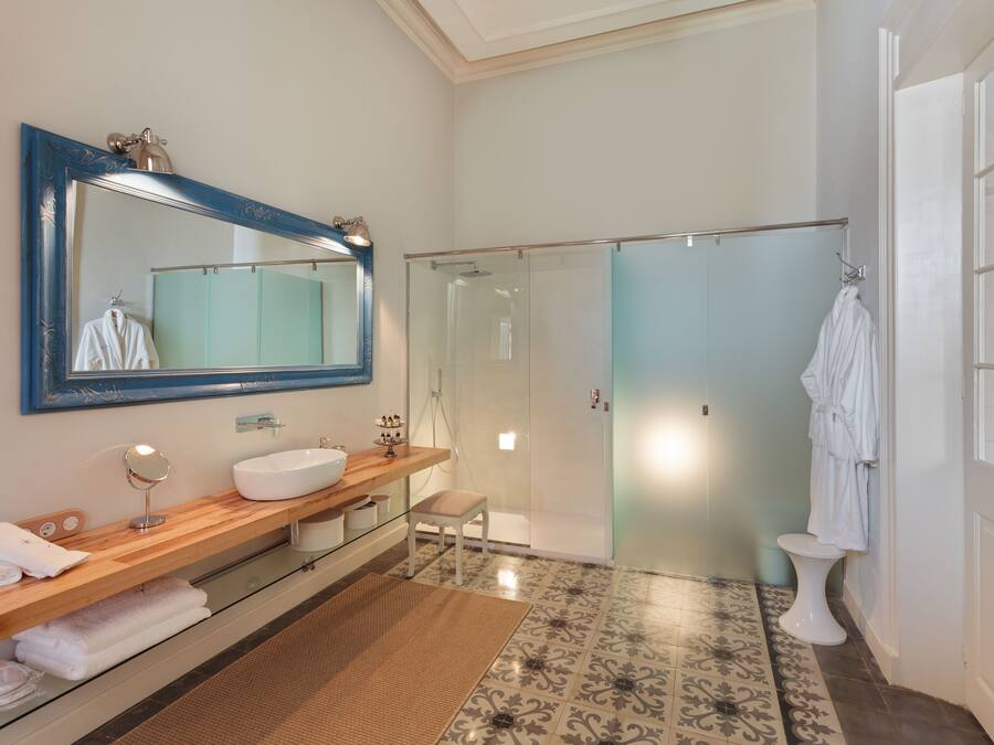 Un baño moderno con tocador de madera, un espejo grande, cabina de ducha de vidrio y un inodoro blanco.
