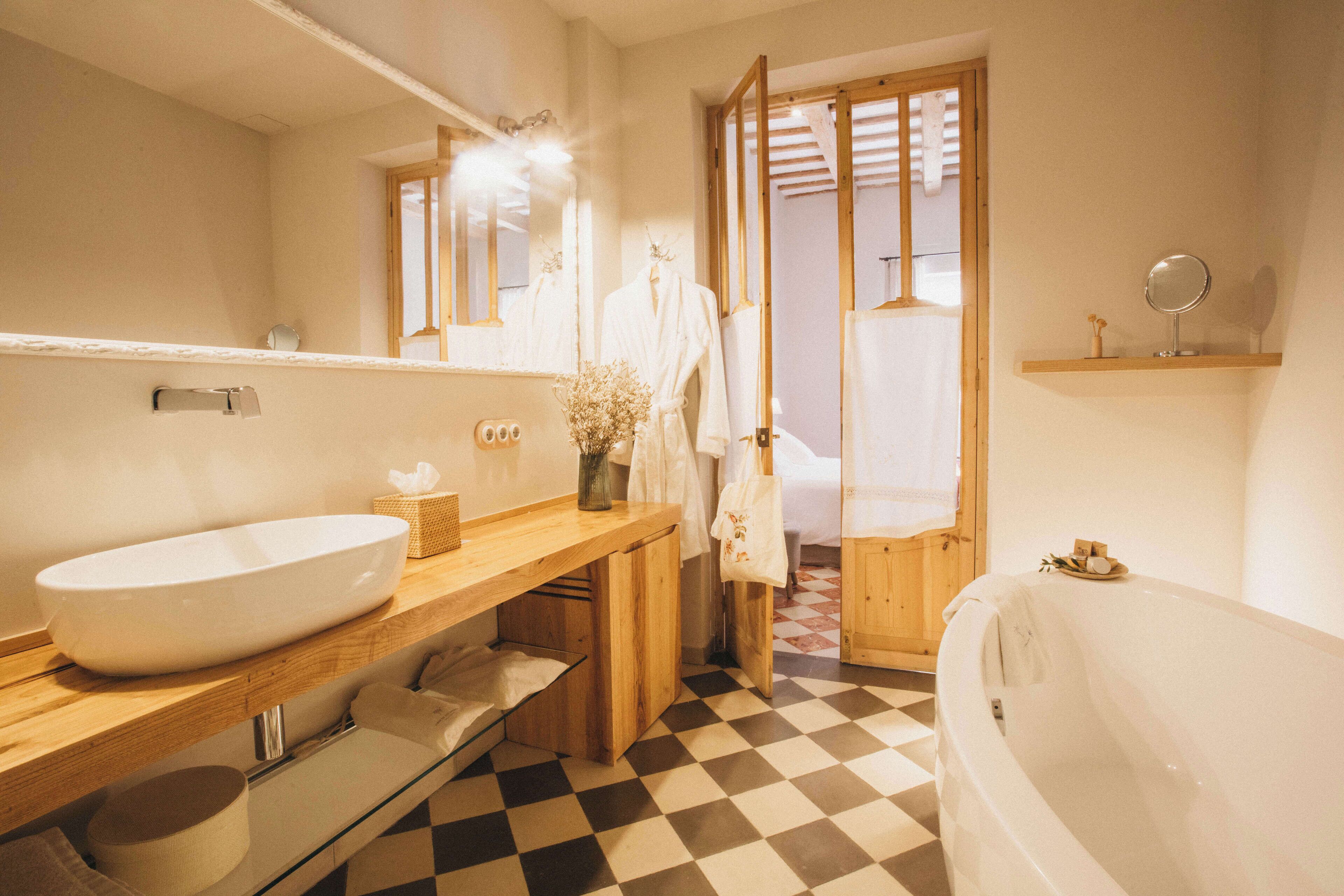 Un baño con tocador de madera, lavamanos blanco, espejo y bañera.