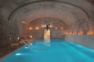 Una piscina interior con techos de piedra en arco y una estatua central.