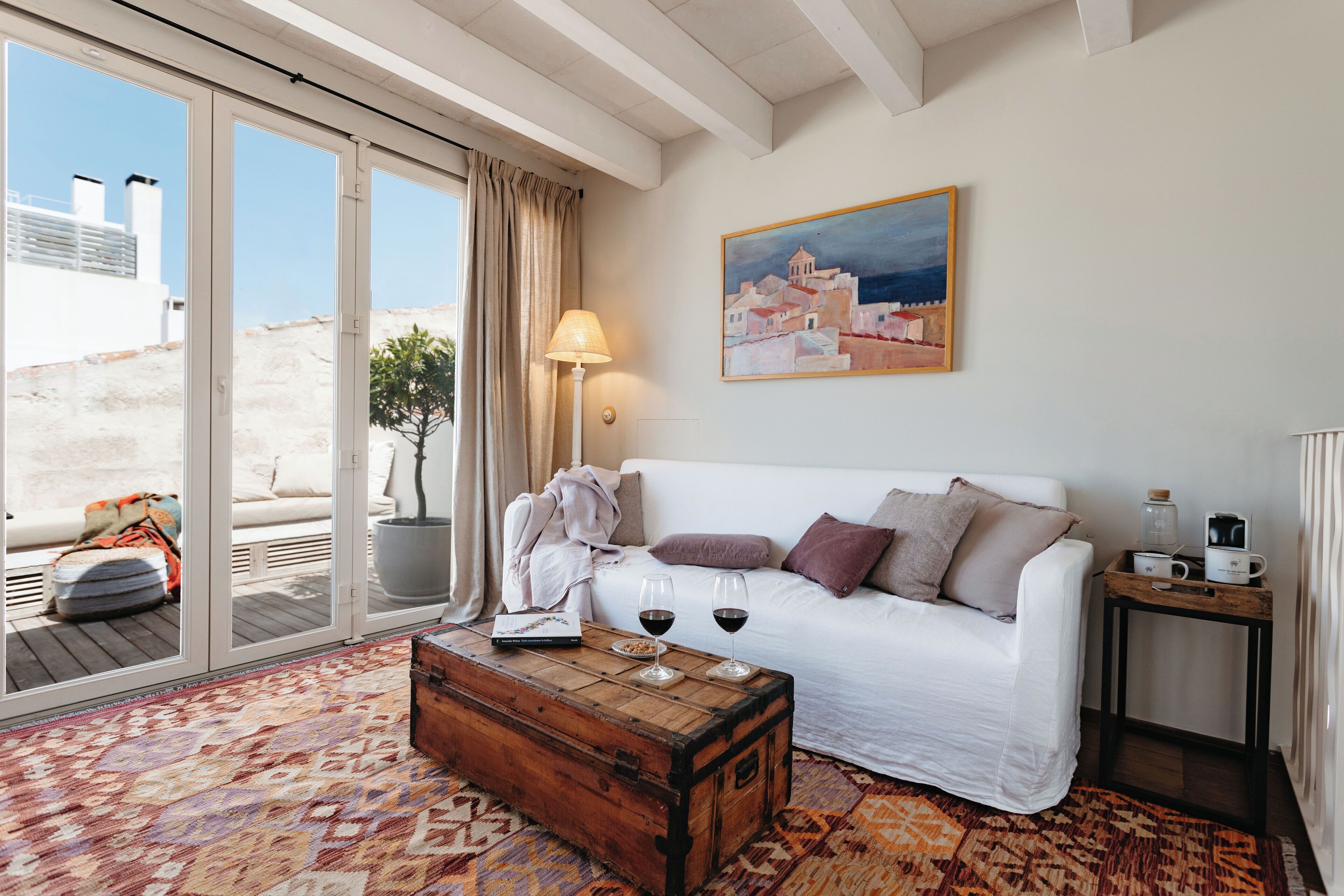 Un salon chaleureux avec un canapé blanc, une table basse en bois et un tableau accroché au mur.