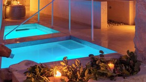 An indoor pool area with a stone archway, a wooden bench, and candles. - Jardí de ses Bruixes Boutique Hotel (Mahón)