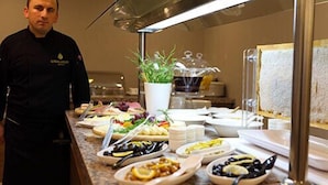 A chef standing in a kitchen with various dishes and a potted plant on the counter. - Luxor Garden Hotel (Izmit)