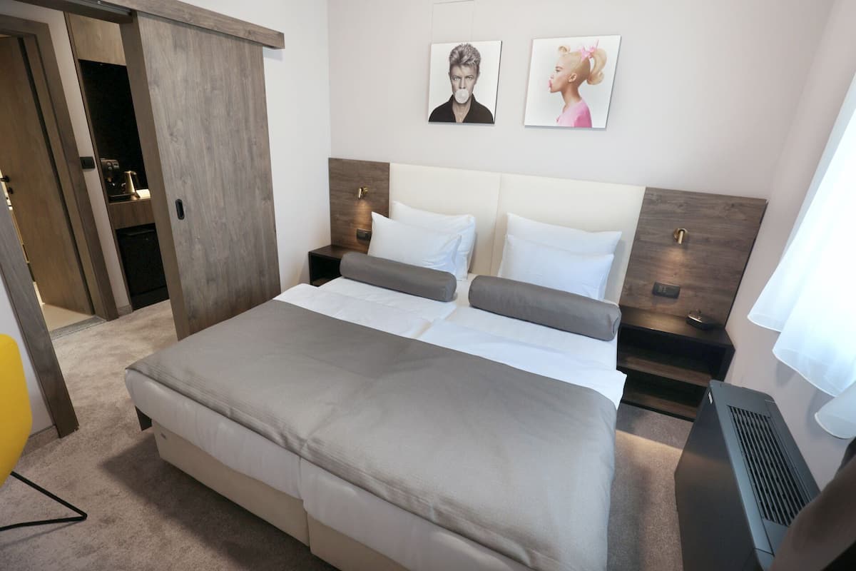 A modern hotel room with a large bed, two bedside tables, and a wall-mounted TV.