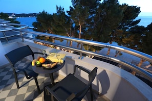 A terrace with a table set for two, featuring a fruit basket, a bottle, and a book. - Hotel Milenij (Makarska)