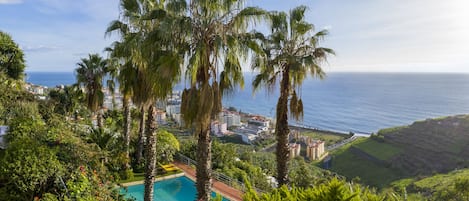 Una piscina al aire libre, sombrillas, sillones reclinables de piscina