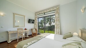 A bedroom with a large bed, a desk, a chair, a television, and a view of the outdoors. - Casa do Papagaio Verde (Funchal)