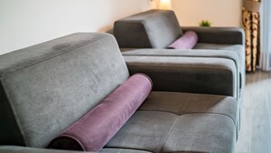 Una hilera de sofás grises con cojines morados en un salón moderno.
