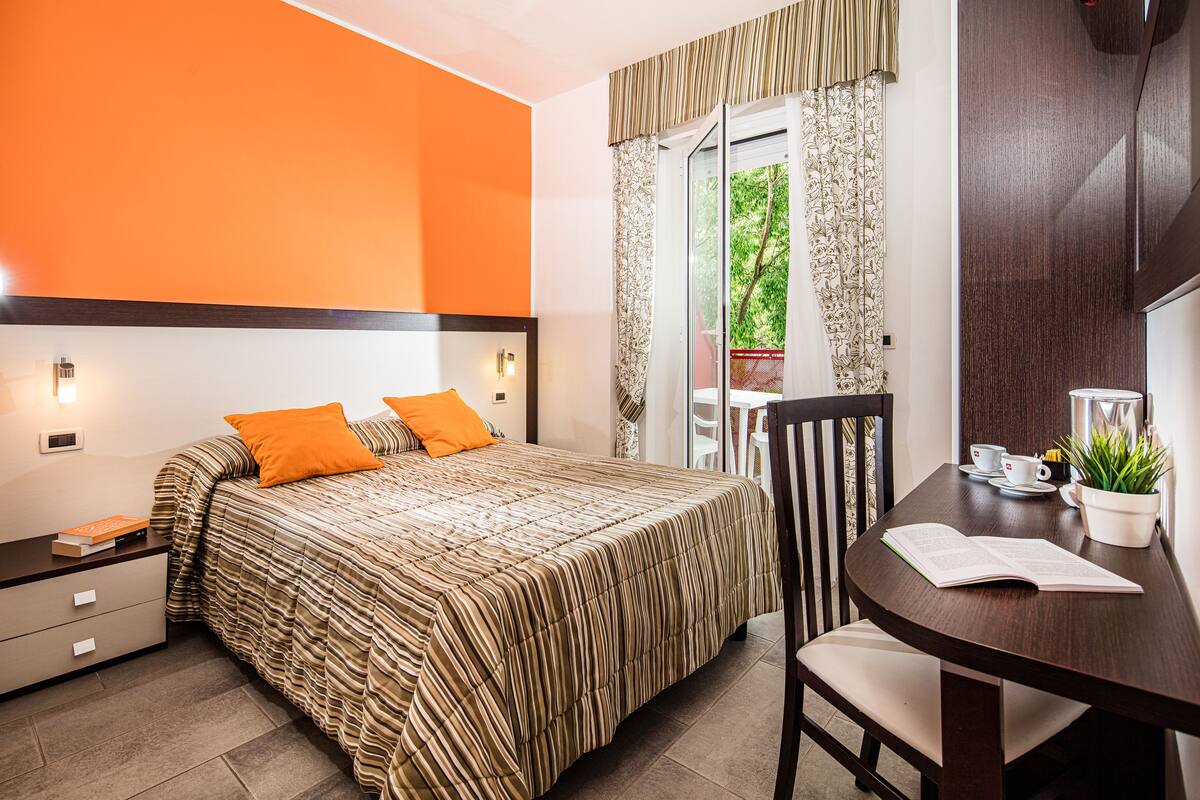 A bedroom with a bed, nightstand, and a table with a chair.