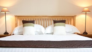A neatly made bed with white linens and two decorative pillows, flanked by two bedside lamps. - The Firgarth - Adults Only (Windermere)