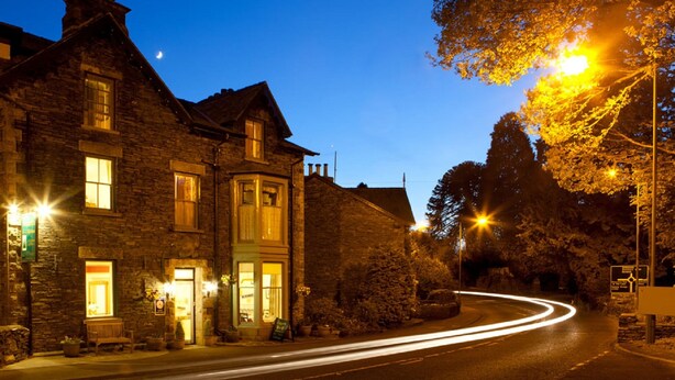 A stone building with multiple windows and a well-lit entrance. - The Firgarth - Adults Only (Windermere)