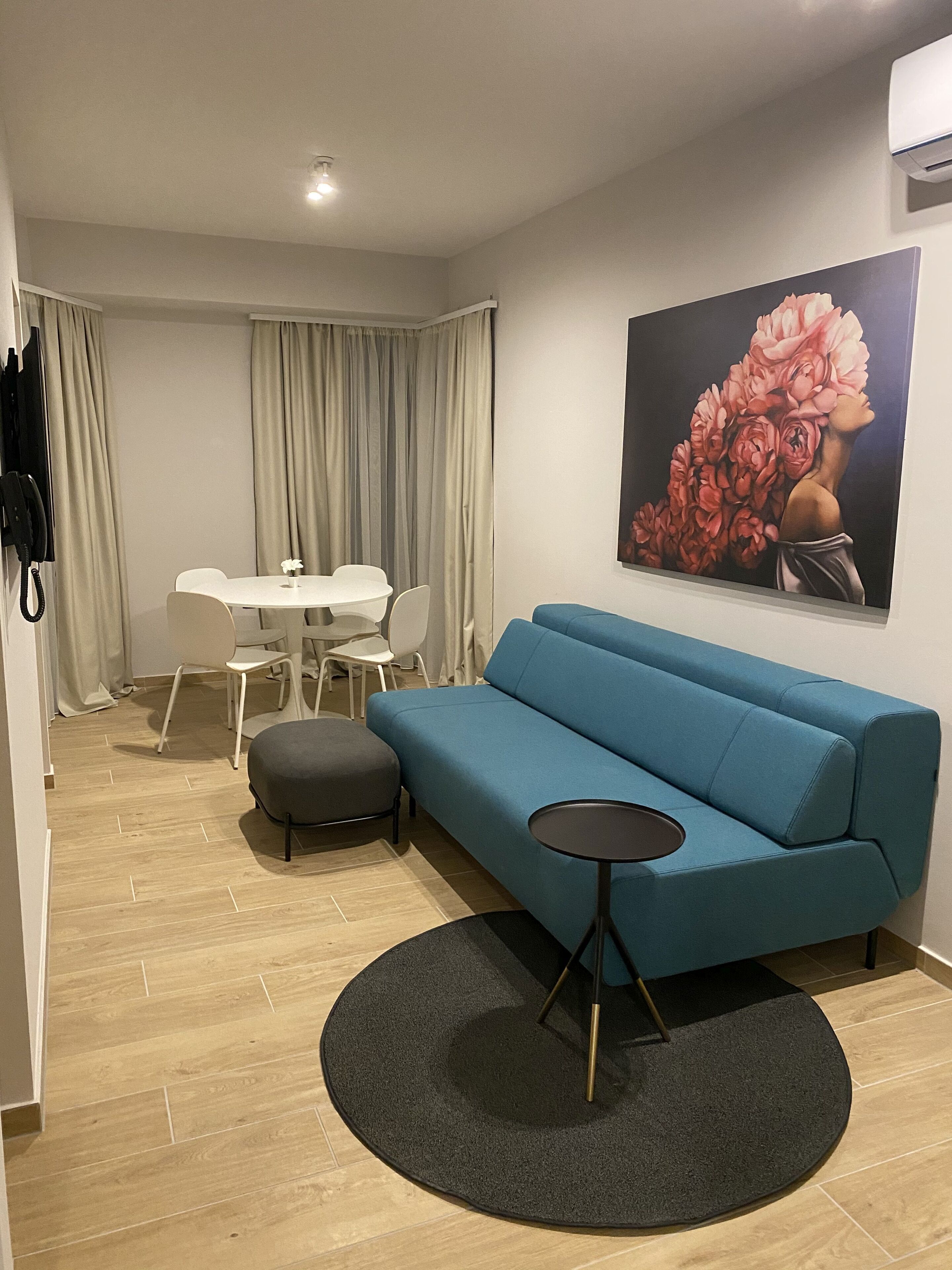 A modern living room with a blue sofa, a round black coffee table, and a dining area with a white table and chairs.