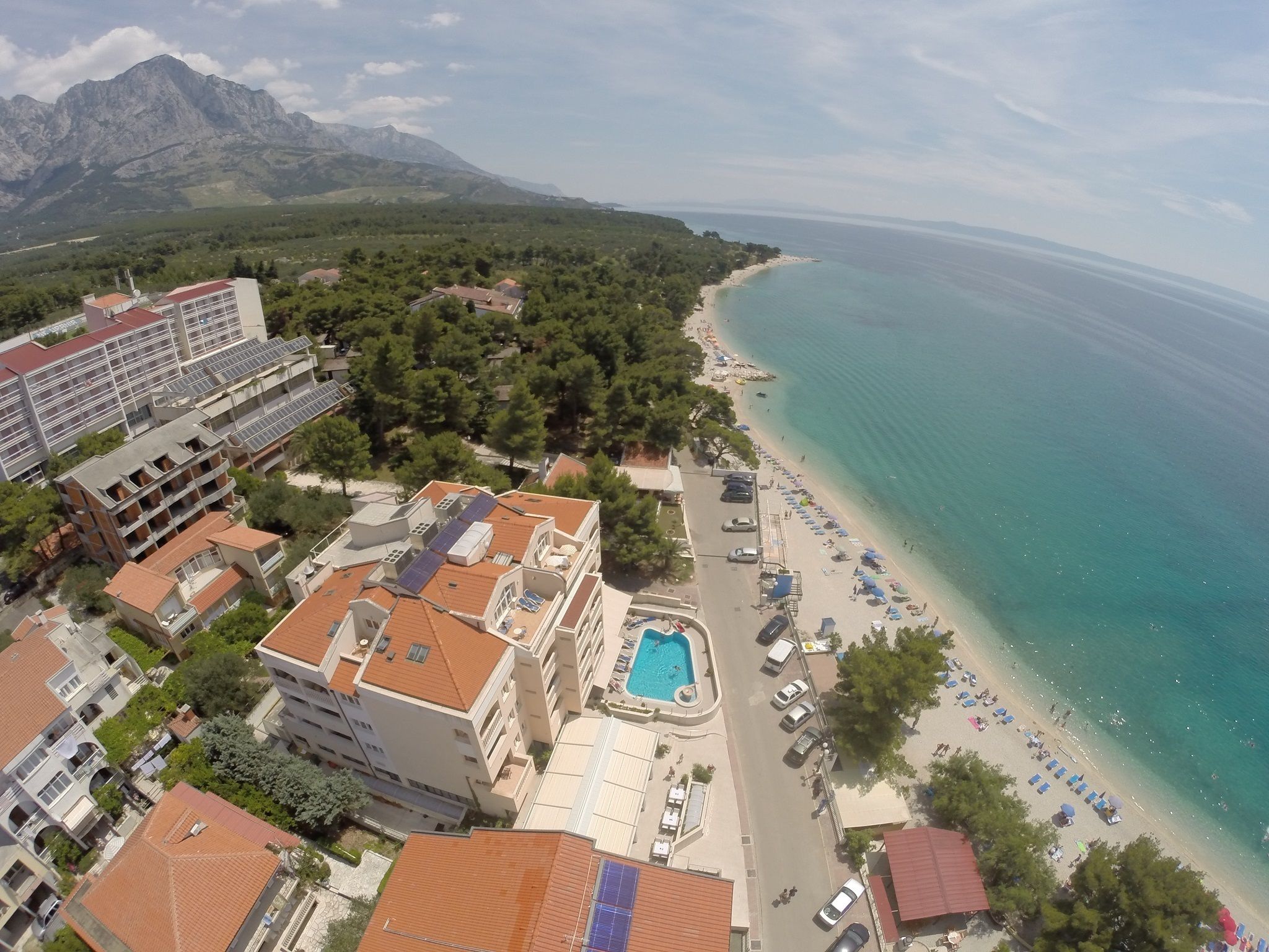 A coastal hotel with a swimming pool, beach access, and mountain views.