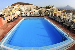Una piscina al aire libre, sillones reclinables de piscina