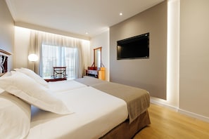 A hotel room with two beds, a desk, a chair, a television, and a large window with curtains. - LABRANDA Hotel Reverón Plaza (Arona)