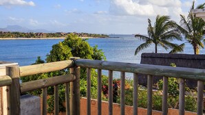 A coastal view with a wooden railing, palm trees, and a beach in the distance. - Beach Paradise Villas (Balaclava)
