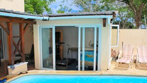 A swimming pool with a covered area, a door leading to a room, and two lounge chairs. - Beach Paradise Villas (Balaclava)