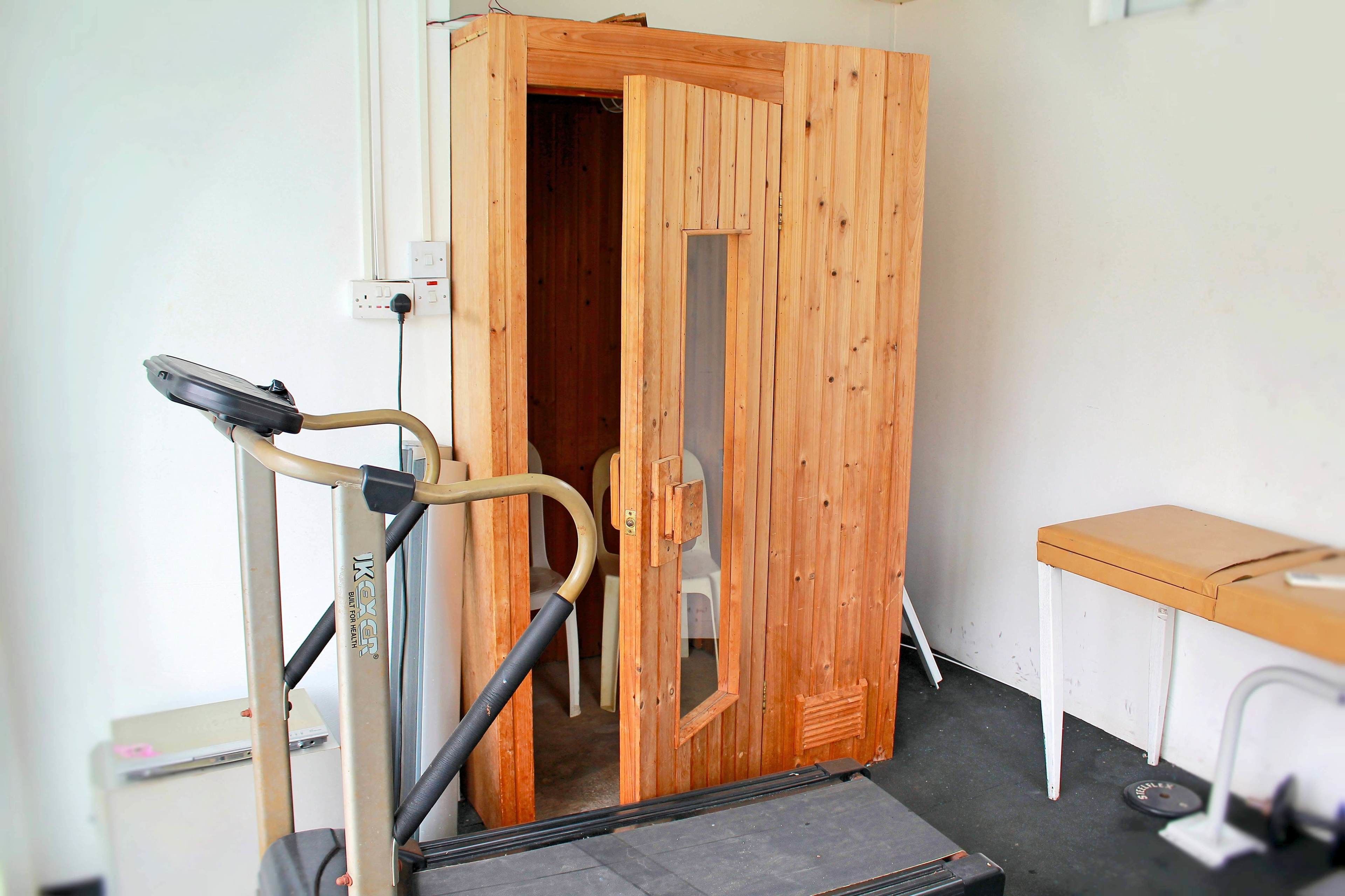 A wooden door with a mirror, a treadmill, and a small table in a room.