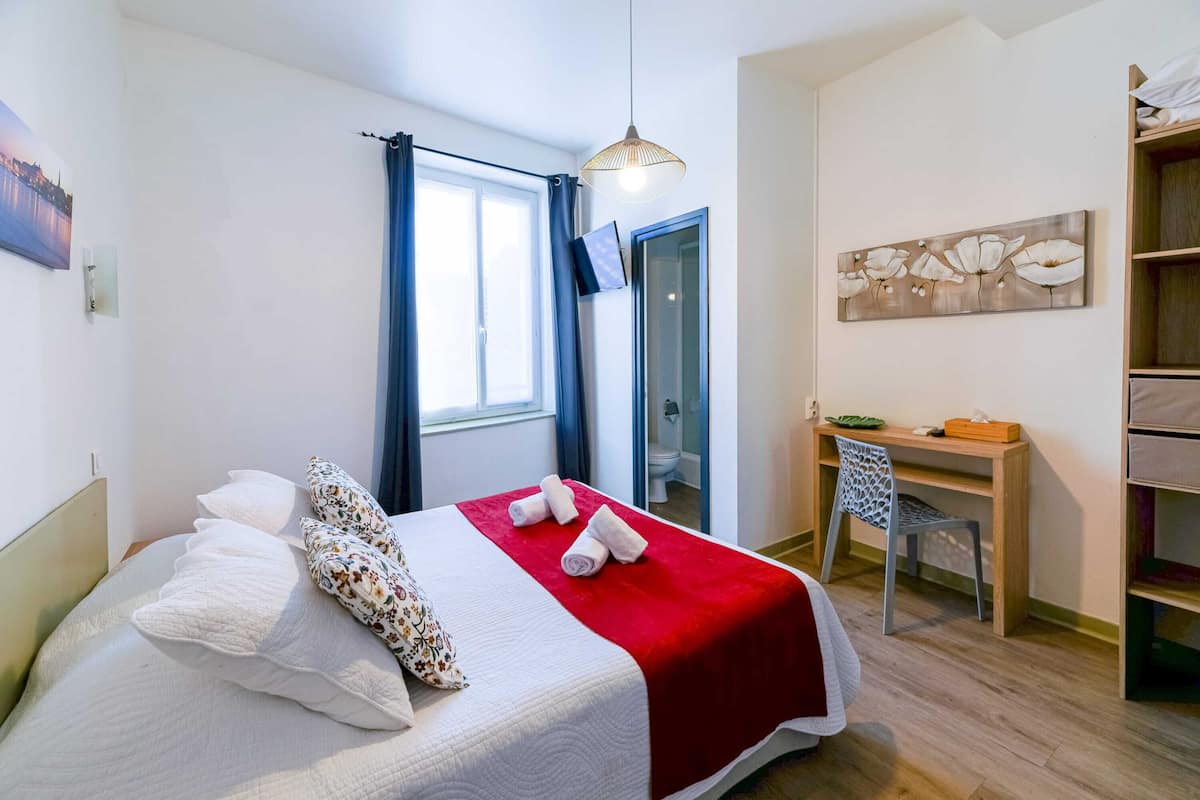 A neatly arranged bedroom with a bed, a desk, and a chair.