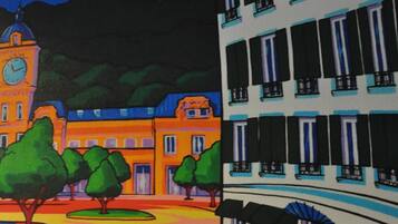 A colorful street scene with a clock tower, trees, and a building labeled "HOTEL COTE BASQUE."