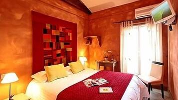 A hotel room with a bed, a desk, a chair, a TV, and a window with curtains.