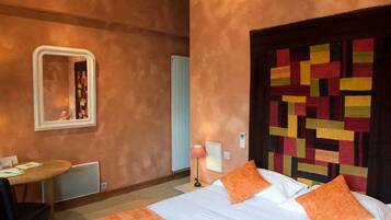 Ein Hotelzimmer mit einem Bett, einem Schreibtisch, einem Stuhl, einem Spiegel und einer Wand mit einer farbenfrohen Stegdecke.