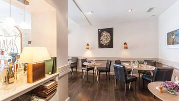 Un restaurant avec des tables et des chaises en bois, un coin bar avec des bouteilles et un luminaire fixé au mur.