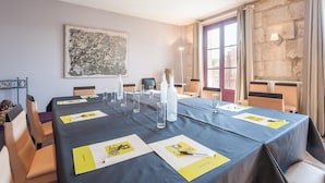 Un salón de conferencias con una larga mesa, sillas y un cuadro en la pared.