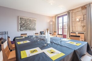 Une salle de conférence avec une longue table, des chaises et un tableau accroché au mur.