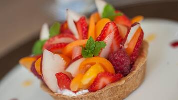 Postre con una variedad de frutas y una hoja de menta encima.