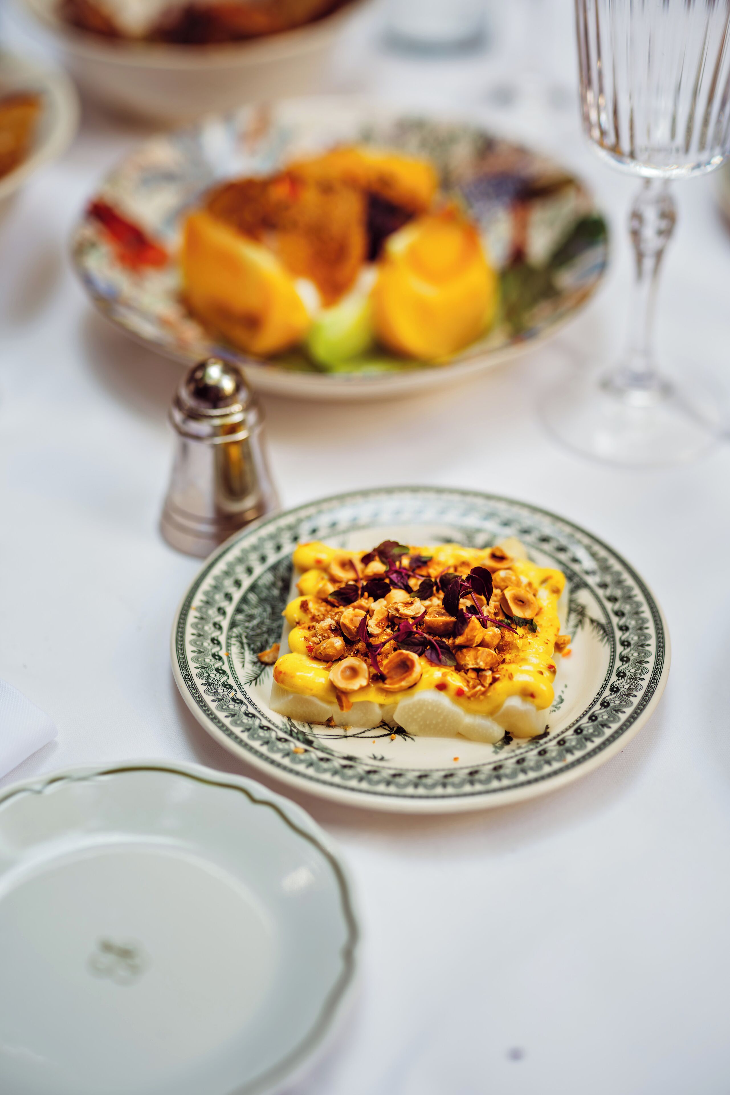 Une table à manger avec une assiette de nourriture, un salier et un verre à vin.