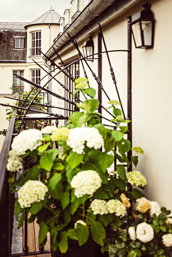 A staircase with a wrought iron railing, white flowers, and a building with multiple windows in the background. - Hôtel Eldorado Paris (Paris)