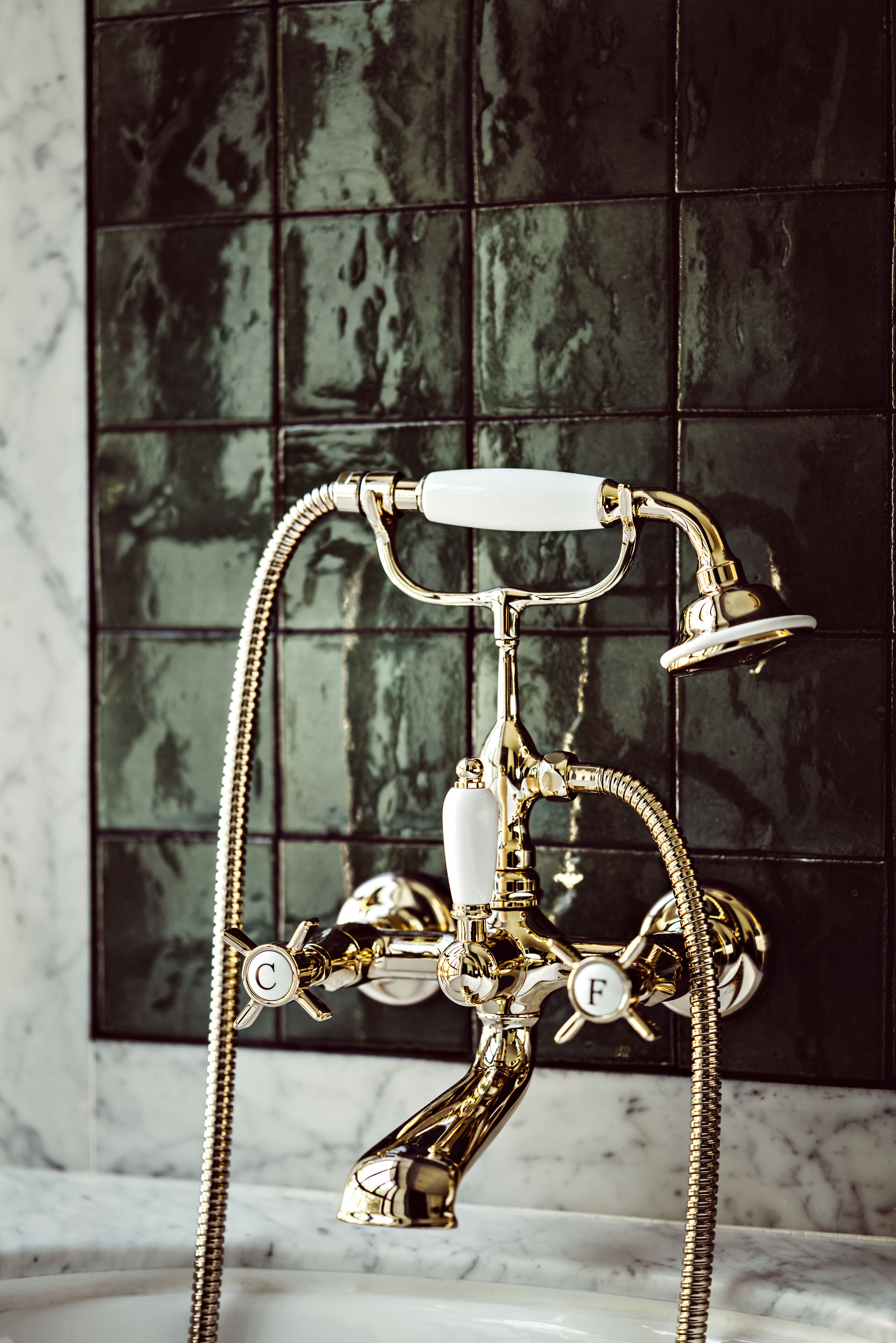 A vintage-style bathroom with a gold-colored bathtub, a separate shower, and a marble sink.