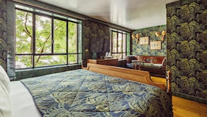 A bedroom with a large bed, a wooden dresser, a desk, and a window with a view of trees. - Hôtel Eldorado Paris (Paris)