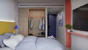 Une chambre moderne avec un lit, une lampe de chevet, une armoire et un téléviseur fixé au mur.