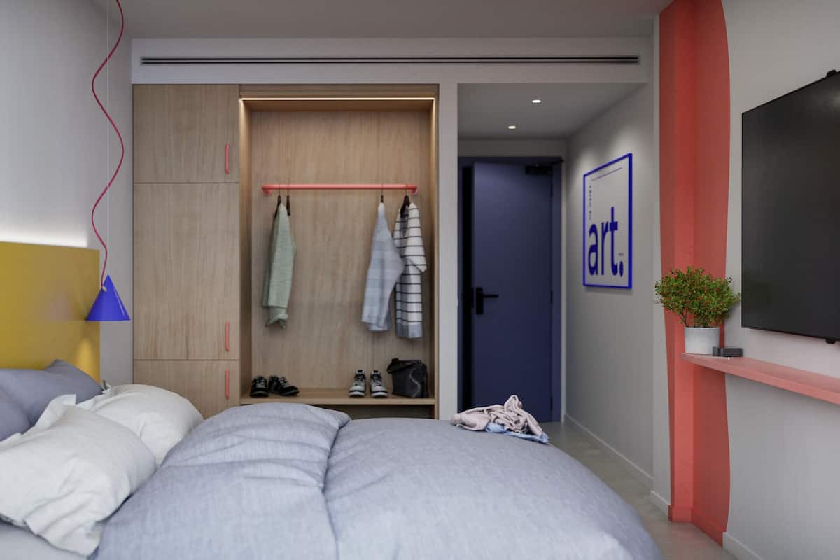 Ein modernes Schlafzimmer mit Bett, Nachttischlampe, Kleiderschrank und einem an der Wand befestigten Fernseher.