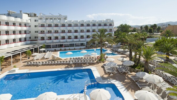Un hôtel doté d’une grande piscine, de nombreuses chaises longues et de parasols.
