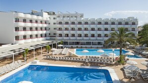 Un hôtel doté de plusieurs piscines, de chaises longues et de parasols.