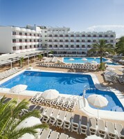 Un hotel con varias piscinas, tumbonas y sombrillas.