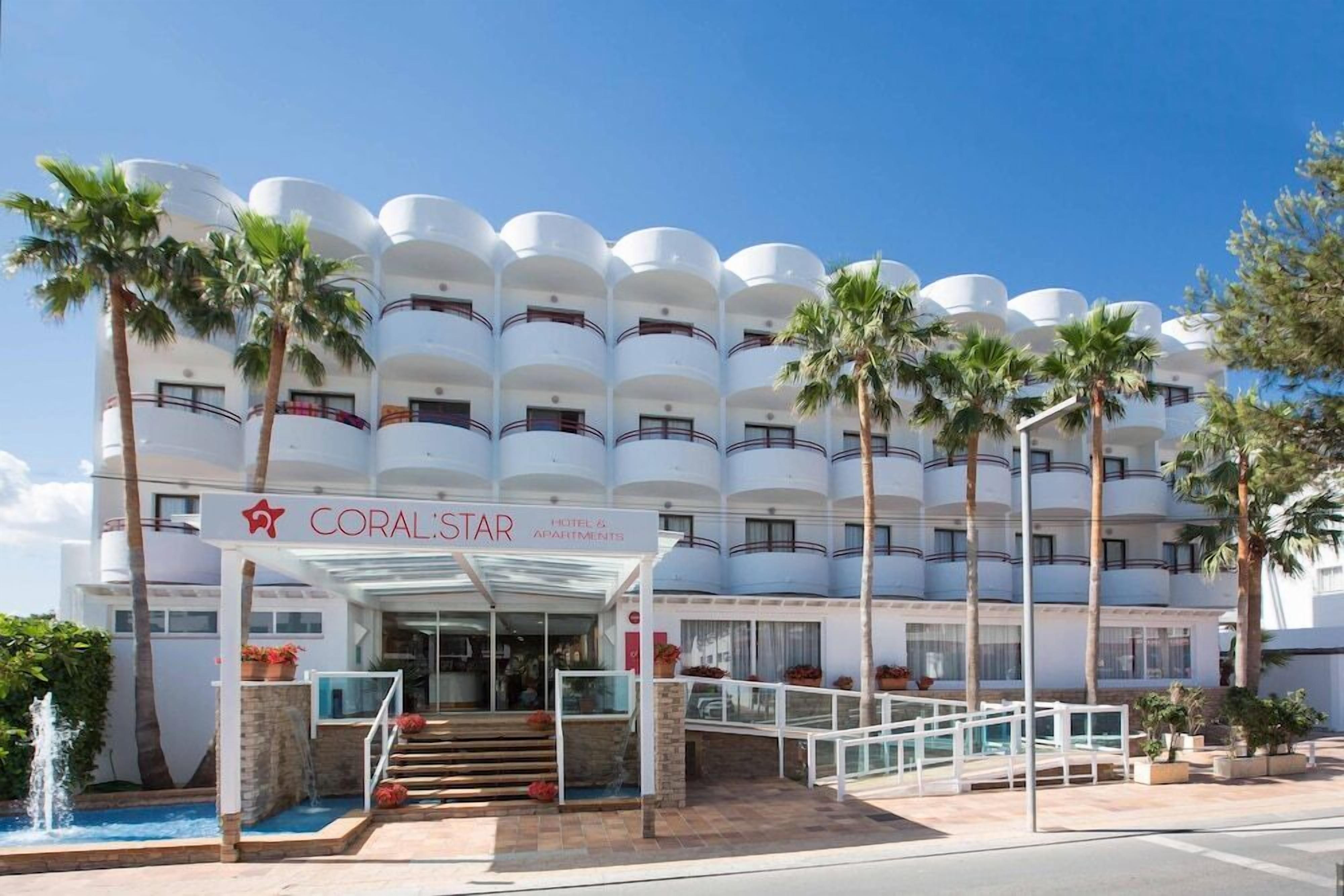 Een meerhoog hotel met een witte gevel, balkons en palmbomen.