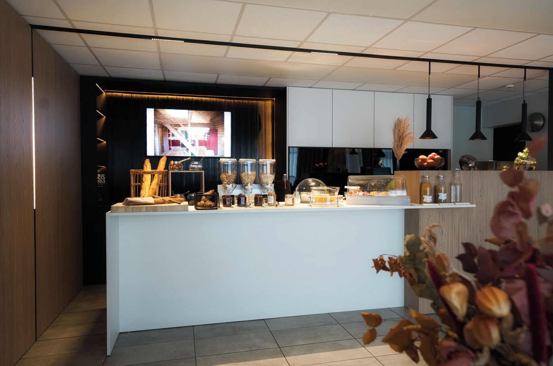 A modern kitchen with a central island, white cabinets, and a view of the outside through a window.