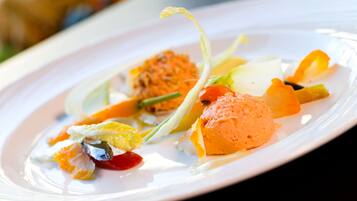 A white plate with a variety of food items including a scoop of orange-colored ice cream, some vegetables, and a small pile of what appears to be shredded cheese or a similar topping.