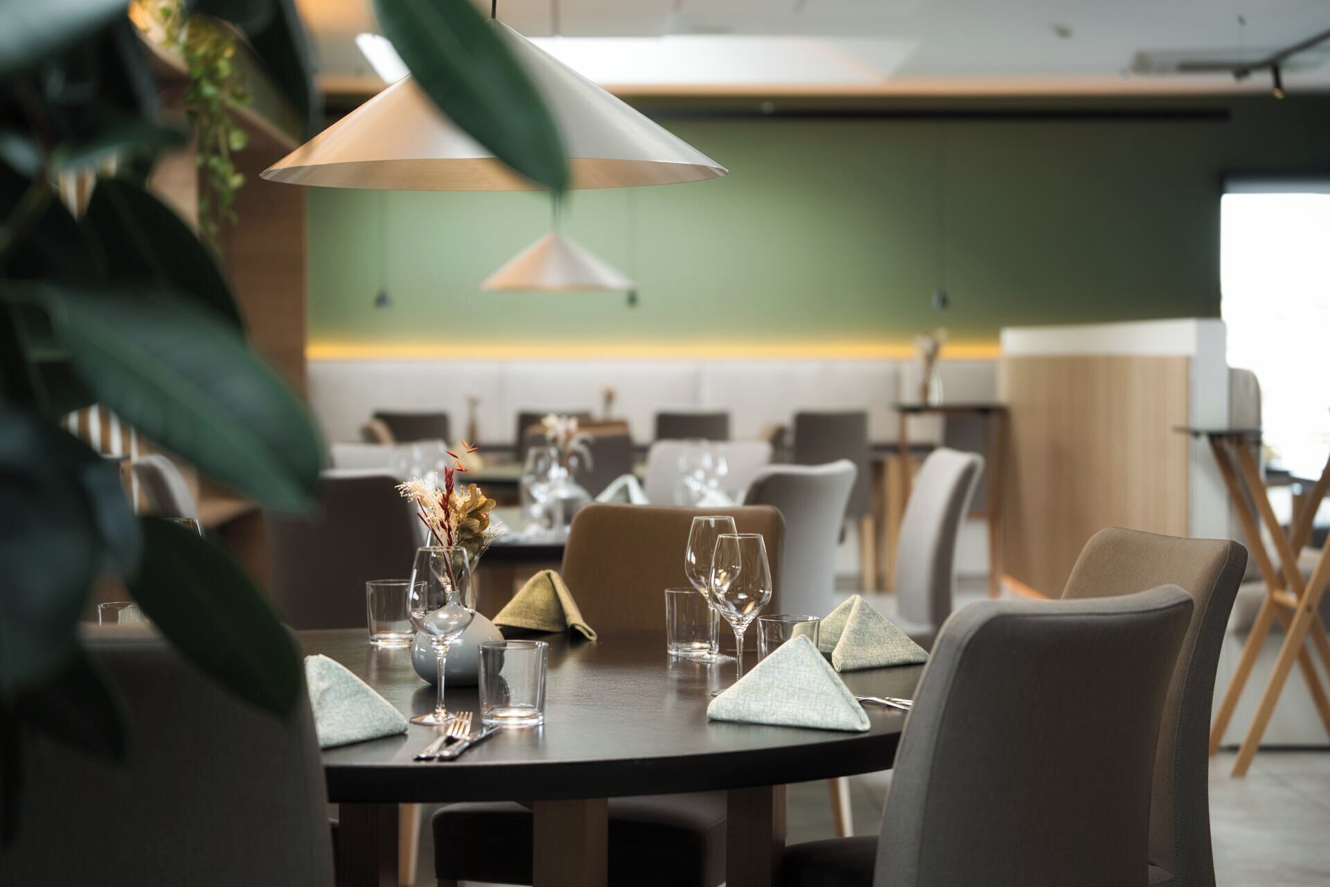 A dining area with tables set for two, featuring clear glassware and napkins.
