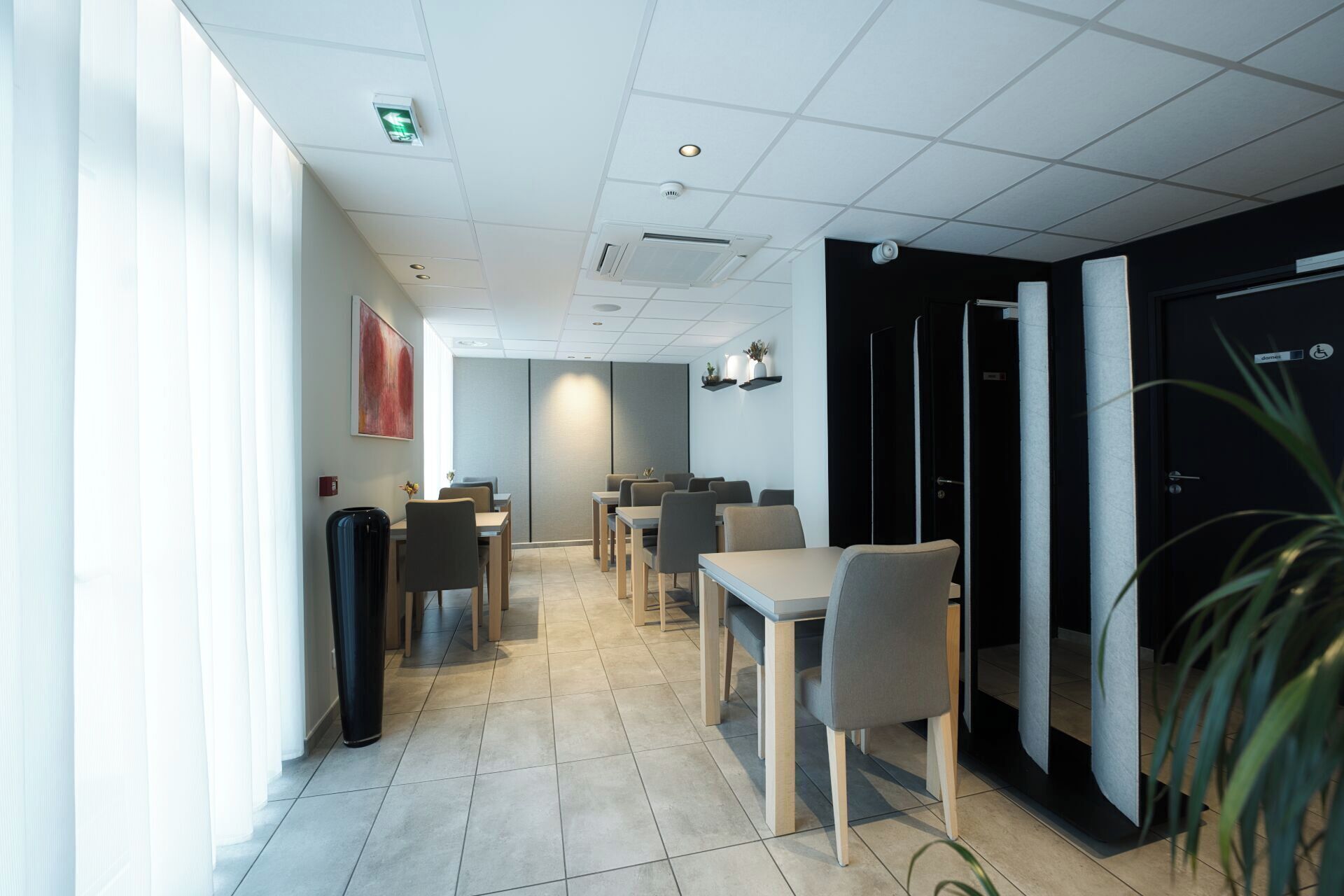 Un hall d’hôtel moderne avec un long couloir, un espace salon et des chambres privées.
