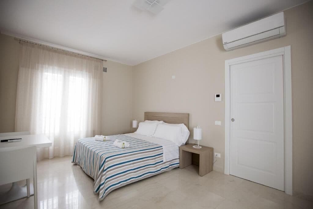 A hotel room with a bed, bedside table, lamp, and a desk.