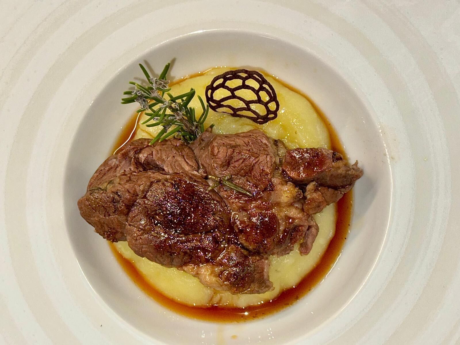 A plate of food with a piece of meat, a garnish, and a sauce.